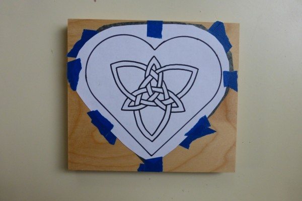 Heart with Celtic knot taped to the top of a wooden box over graphite paper
