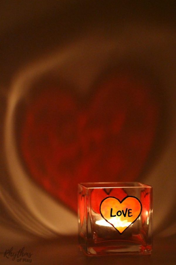 DIY Personalized candle holder with red hearts casting on the wall and the word "love" written on it for Imbolc blessing