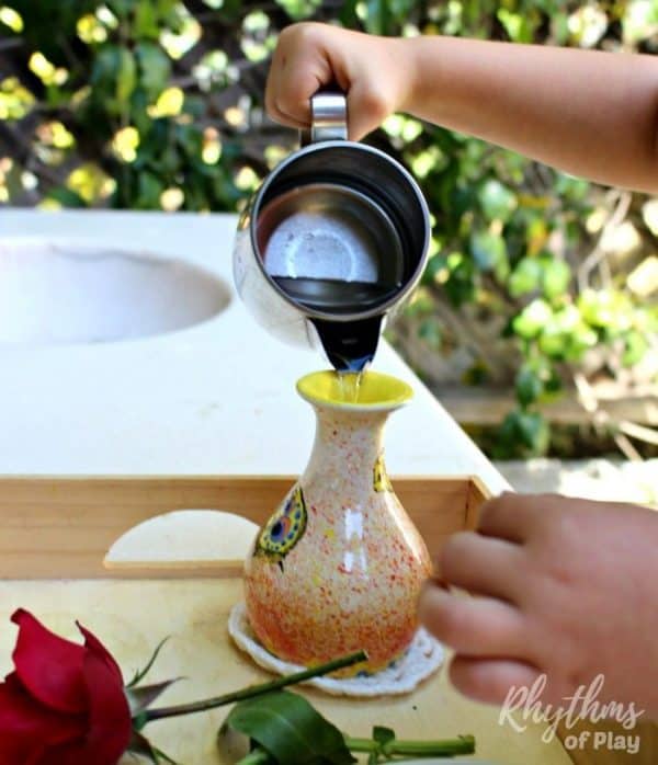child pouring water into vase for flower arranging activity for kids  (C. Kartychok pouring water, photo by Nell Regan K.)