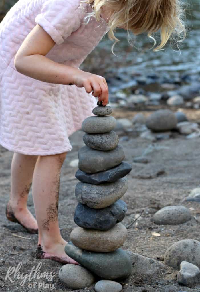 Kid balancing a final rock on the top of a stack of stones