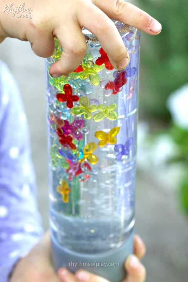 child playing with sensory bottles with butterflies (Photo of C Kartychok's hands playing with DIY calm down jar craft by Nell Regan Kartychok)