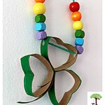 DIY Shamrock necklace crafts for St. Patrick's Day made with recycled toilet paper rolls, yarn, and colored beads.