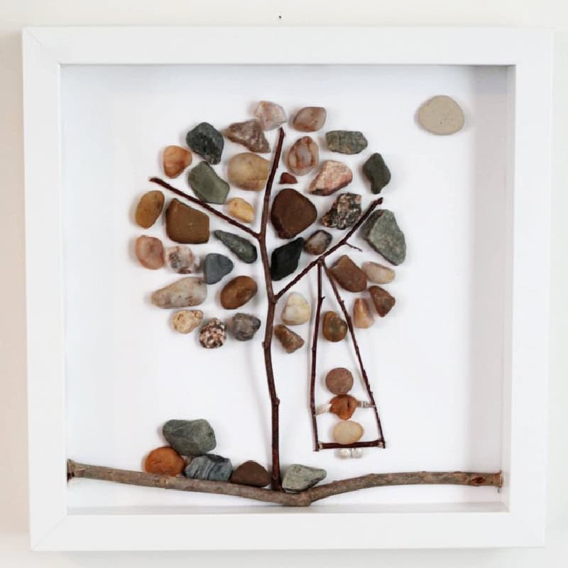 pebble craft: autumn tree with a girl on a swing made with pebbles and twigs