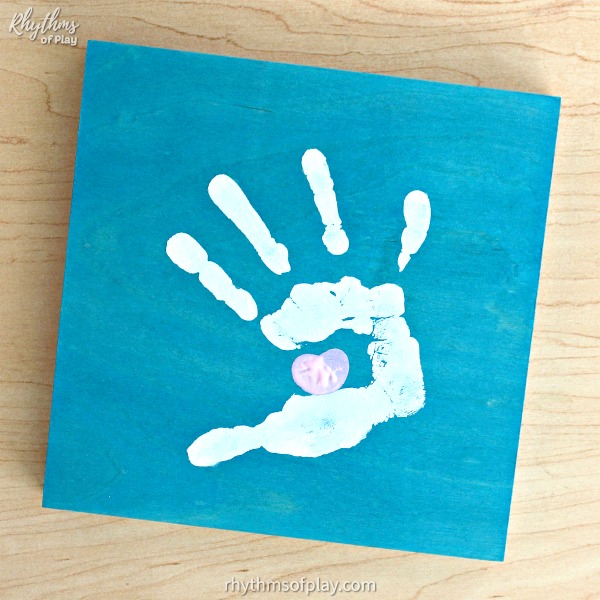 Homemade "Kissing hand" handprint art craft with a thumbprint heart on blue wood canvas