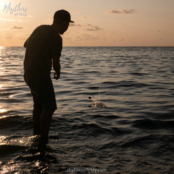 silhouette of a teenage boy skipping a stone across water