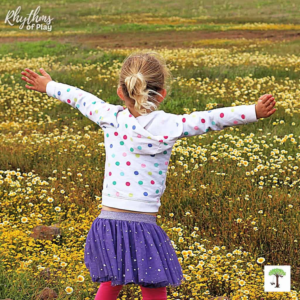 Preschool girl spotting a field of wildflowers on spring scavenger hunt.