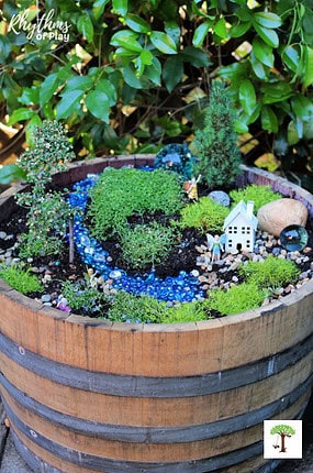 Fairy garden DIY tutorial in a half-wine barrel to attract fairies to your garden.