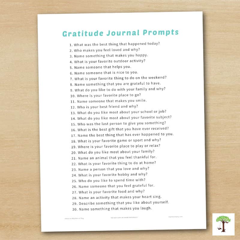 photograph of printable list of gratitude journal prompts on a wooden tabletop