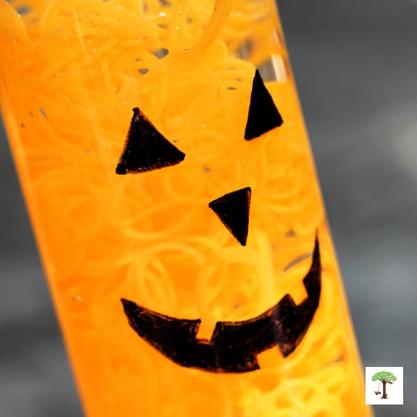Halloween pumpkin sensory bottle with a glowing friendly pumpkin face