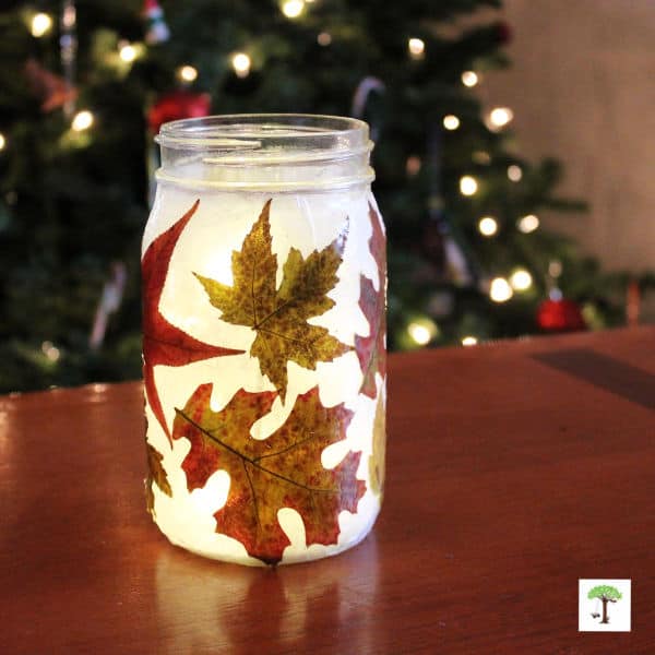 handmade fall leaf lantern on a table illuminated with lights and candles