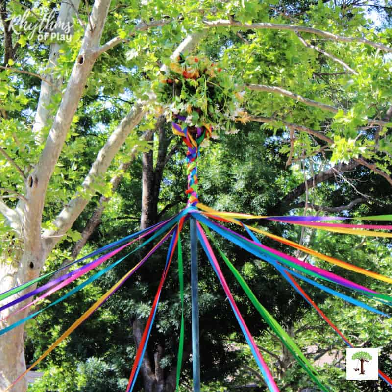 Maypole dance tradition with colorful ribbons wrapping around the maypole with a basket of flowers on top