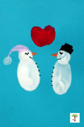 Fingerprint snowman craft with fingerprint snow-woman and thumprint heart between them stamped on a blue blank greeting card.