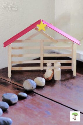 DIY popsicle stick nativity stable craft with wooden peg doll holy family.