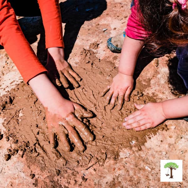 toddler and preschooler finger painting with mud.