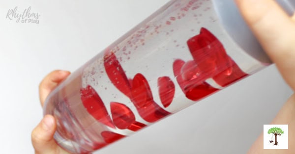 Kid playing with sensory bottle toy filled with hearts for Valentine's Day,