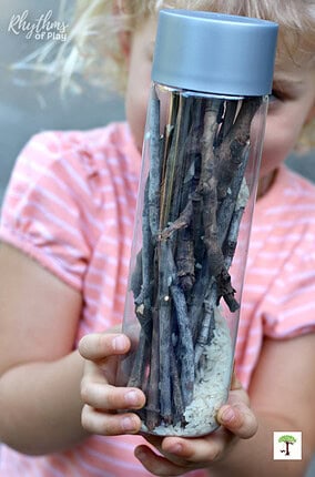Kid playing with a DIY rainstick sensory bottle made with recycled and naturally sourced ingredients.